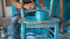 An image of someone painting a chain with paint stains on their clothing