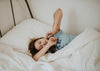 A woman stretching after waking up in bed.