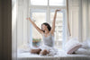 Woman sitting in bed stretching before sleep.