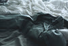 grey and white sheets on a bed.